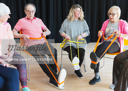 Active seniors exercising in circle, using straps to stretch legs