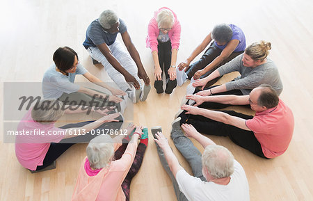 Active seniors stretching legs in circle in exercise class