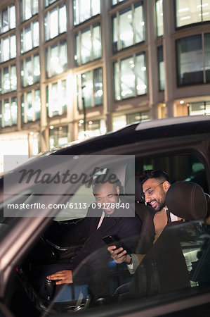 Businessman showing smart phone to driver in crowdsourced taxi