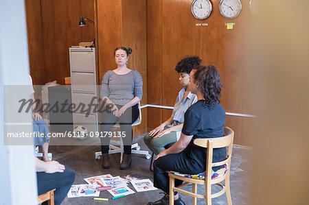 Serene, creative businesswomen meditating in circle, taking a break in meeting Serene, creative businesswomen meditating in circle, taking a break in meeting