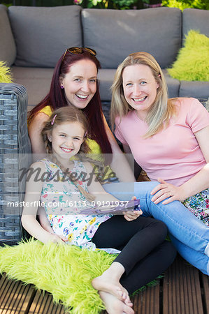 Portrait happy lesbian couple and daughter relaxing on patio