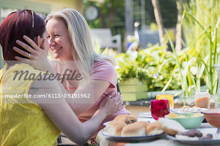 Affectionate lesbian couple enjoying lunch at patio table