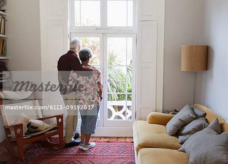 Affectionate, serene senior couple looking out living room window