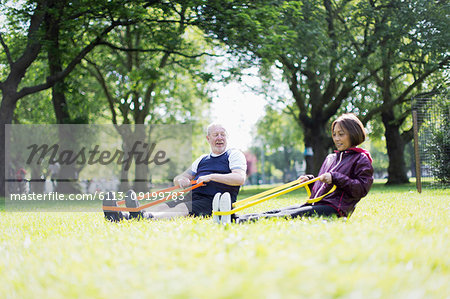 Active senior couple exercising, using resistance bands in park