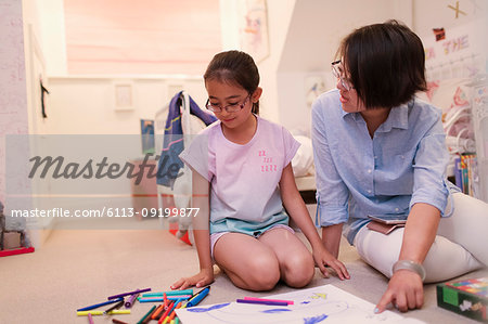 Mother and daughter coloring on bedroom floor