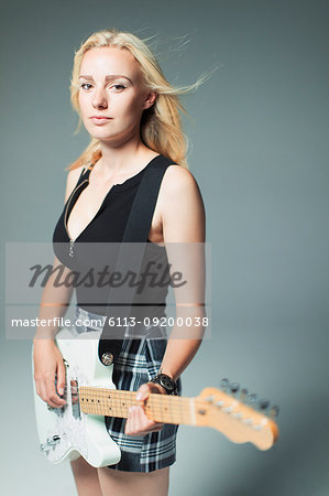 Portrait confident, cool young woman playing electric guitar