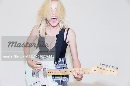 Portrait exuberant young woman playing electric guitar