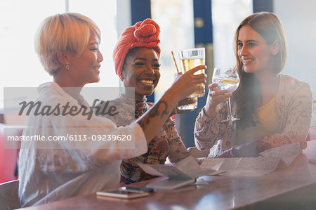 Happy, carefree young women friends toasting cocktail glasses in bar
