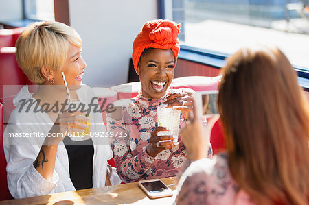 Happy young women friends drinking cocktails and laughing in restaurant