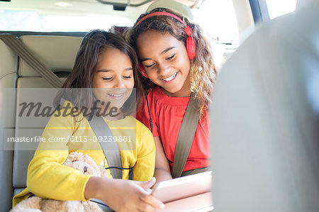Sisters using digital tablet in back set of car