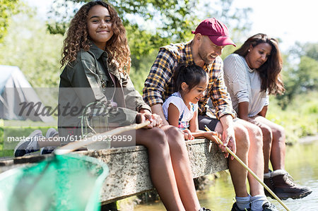 Portrait smiling girl fishing with family on dock