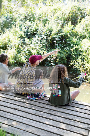 Family blowing bubbles on dock in woods