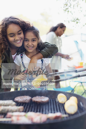 Portrait affectionate sisters enjoying barbecue