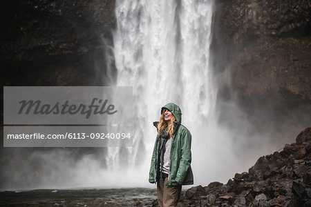 Smiling female hiker in rain jacket at waterfall, Whistler, British Columbia, Canada