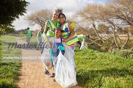 Portrait happy multi-generation women volunteering, cleaning up litter in sunny park