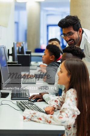 Teacher helping junior high students using computer in computer lab