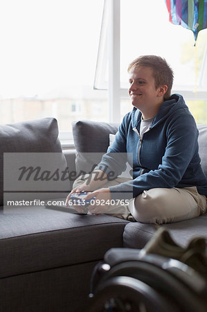 Smiling young woman playing video game on sofa