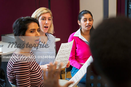 Womens choir with sheet music singing in music recording studio