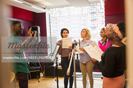 Womens choir with sheet music singing in music recording studio