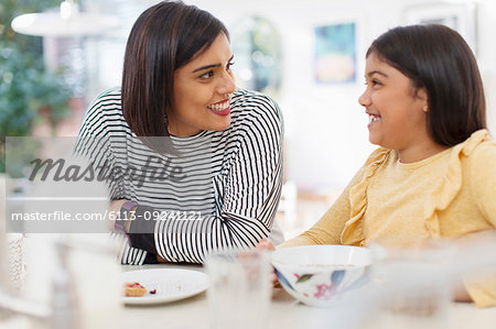 Happy mother and daughter eating breakfast