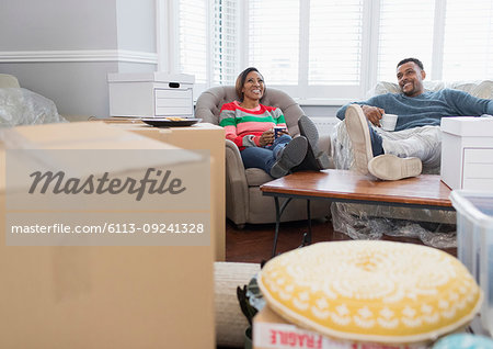 Happy couple moving house, taking a break and drinking tea