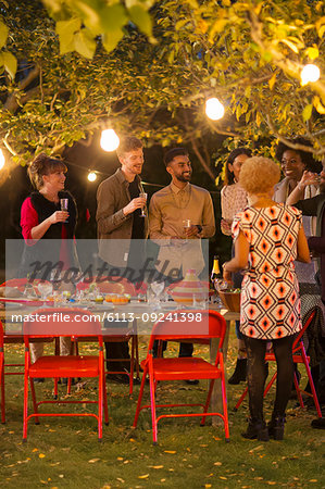 Friends talking under trees at dinner garden party