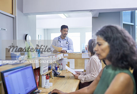 Doctor and receptionist talking at clinic reception