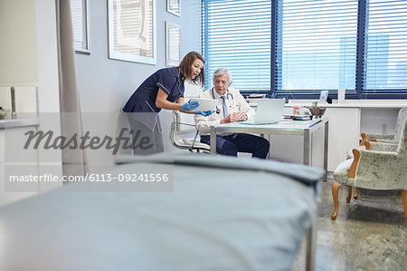 Doctor and nurse using digital tablet, consulting in clinic doctors office