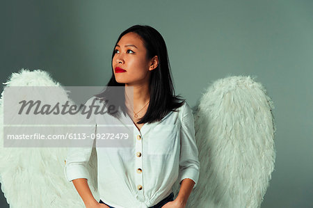 Serene, curious young woman wearing angel wings