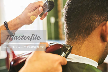 Close up male barber using trimmer on hair of customer