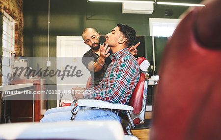 Male barber and customer in barbershop