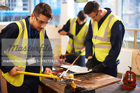 Male students using equipment in shop class workshop