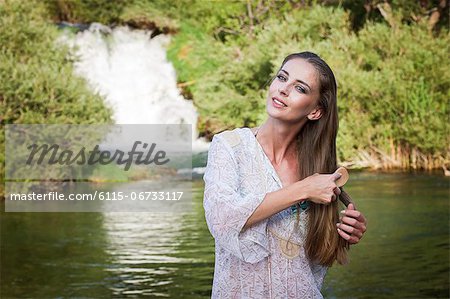 Croatia, Dalmatia, Young woman combing her hair, waterfall in background