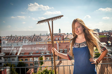 Woman On Roof Terrace Holding Garden Rake, Munich, Bavaria, Germany, Europe