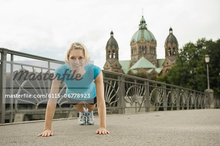 Young woman doing push-ups on bridge, Munich, Bavaria, Germany