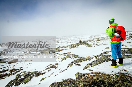 Speed hiker taking a look at mountain range, snowcapped, Norway, Europe
