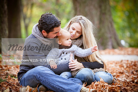 Family with son sits among autumn leaves, Osijek, Croatia