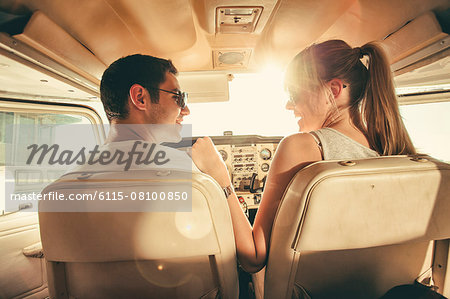 Young couple sitting in cockpit of propeller airplane