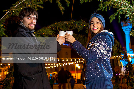 Young couple toasting with punch at Christmas Market