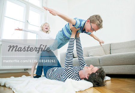 Father playing with two children in living room