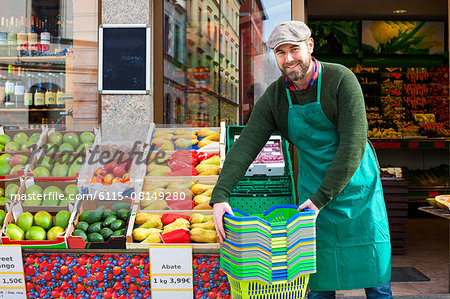 Grocer arranging shopper baskets in front of greengrocer's shop