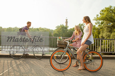 Group of friends riding bicycle on city bridge