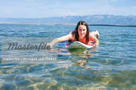 Woman lying on surfboard
