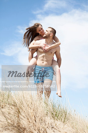 Free Photo  Man giving piggyback ride to woman on the beach