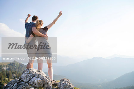 Young couple cheering on mountain peak