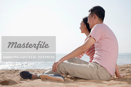 Couple sitting on the beach and looking out at the ocean