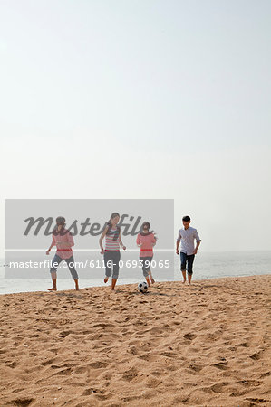 Young Friends Playing Soccer on the Beach