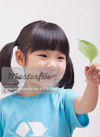 Little girl looking at leaf, close up studio shot