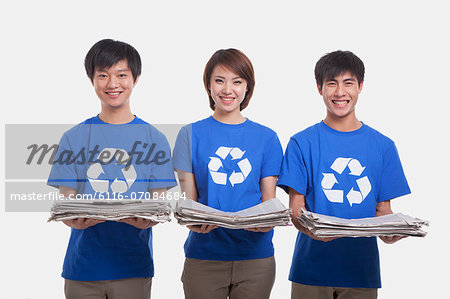 Three young people carrying newspapers, studio shot