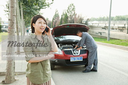 Woman Talking on Phone While Mechanic Fixes Her Car